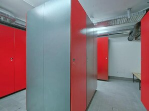 Baño con taquillas rojas y un tabique gris.