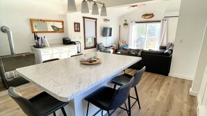 A modern kitchen with a large island, black chairs, and a dining area with a black sofa.