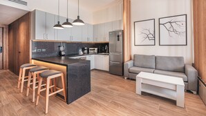 A modern kitchen with a central island, bar stools, a built-in oven, and a refrigerator. - Probar Suites Punta Cana (Punta Cana)