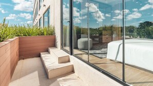 A modern outdoor balcony with a glass door leading to a bedroom. - Probar Suites Punta Cana (Punta Cana)