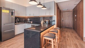 A modern kitchen with a central island, bar stools, stainless steel appliances, and pendant lighting. - Probar Suites Punta Cana (Punta Cana)