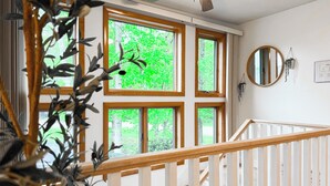A staircase with white railings and a view of a green landscape through large windows.