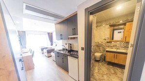 A modern kitchen with dark cabinets, a stainless steel sink, and a marble backsplash. - Çamlıca Park Otel (Of)
