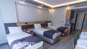 A modern hotel room with three beds, a kitchenette, and a dining area. - Çamlıca Park Otel (Of)