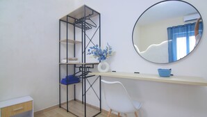 A room with a desk, chair, mirror, and a shelving unit with clothes and a vase. - DOMUS GREEN 20 minutes from the Vatican and the Historic Center of Rome (Roma)