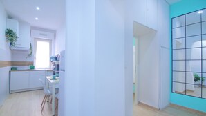 A modern kitchen with white cabinets, a dining table with chairs, and a window with natural light. - DOMUS GREEN 20 minutes from the Vatican and the Historic Center of Rome (Roma)