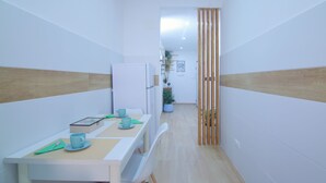 A narrow hallway with a dining area featuring a table with chairs, a refrigerator, and a potted plant. - DOMUS GREEN 20 minutes from the Vatican and the Historic Center of Rome (Roma)