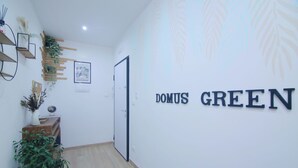 A hallway with a sign reading "DOMUS GREEN" on the wall, wooden flooring, and a potted plant. - DOMUS GREEN 20 minutes from the Vatican and the Historic Center of Rome (Roma)