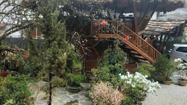 A courtyard with a wooden bridge, potted plants, and a thatched-roof structure. - An's Space Sapa (Sa Pa)