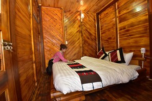 A wooden cabin room with a bed, a nightstand, and a wall-mounted lamp. - An's Space Sapa (Sa Pa)