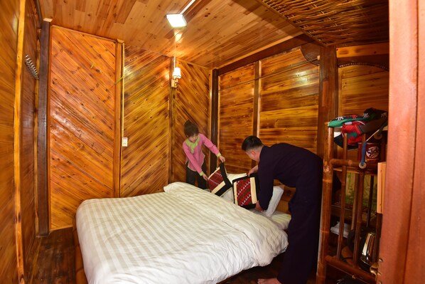 A wooden cabin room with a bed, a shelf with items, and a wall-mounted light fixture. - An's Space Sapa (Sa Pa)