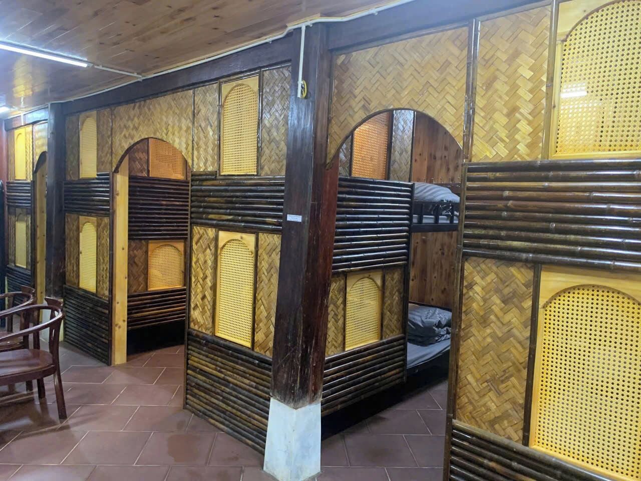 A room with bunk beds, wooden walls, and a tiled floor.