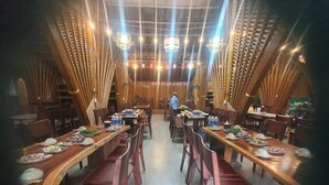 A restaurant with long wooden tables and chairs, arranged in a central aisle. - An's Space Sapa (Sa Pa)