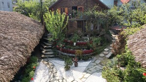 A wooden house with a thatched roof, surrounded by a garden with stepping stones and various plants. - An's Space Sapa (Sa Pa)