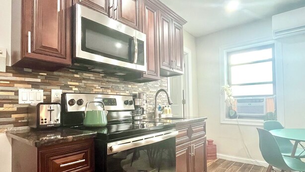Una cocina con armarios de madera oscura, un microondas de acero inoxidable, una estufa y un lavavajillas.