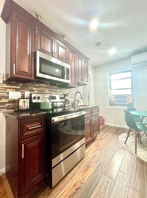 Una cocina con armarios de madera oscura, un microondas de acero inoxidable, una estufa y un lavavajillas.