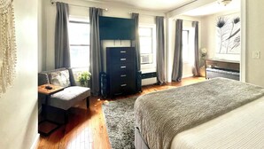 Un dormitorio con cama, escritorio, cómoda y ventilador de techo.