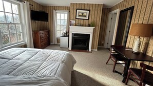 A bedroom with a bed, dresser, desk, chair, fireplace, and a television on the wall. - The Bond Inn Room #9 (Warrensburg)