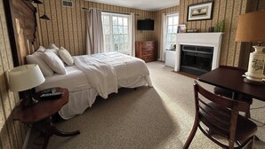 A bedroom with a bed, bedside tables, a dresser, a fireplace, and a television. - The Bond Inn Room #9 (Warrensburg)