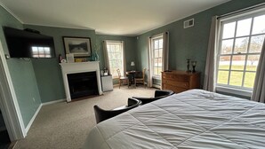 Une chambre à coucher avec un grand lit, une cheminée, un téléviseur et une vue sur l’extérieur par une fenêtre.