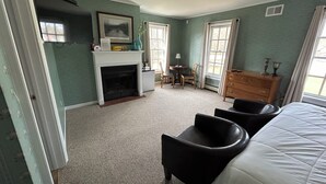 Une chambre d’hôtel avec une cheminée, un lit, un bureau et une commode.