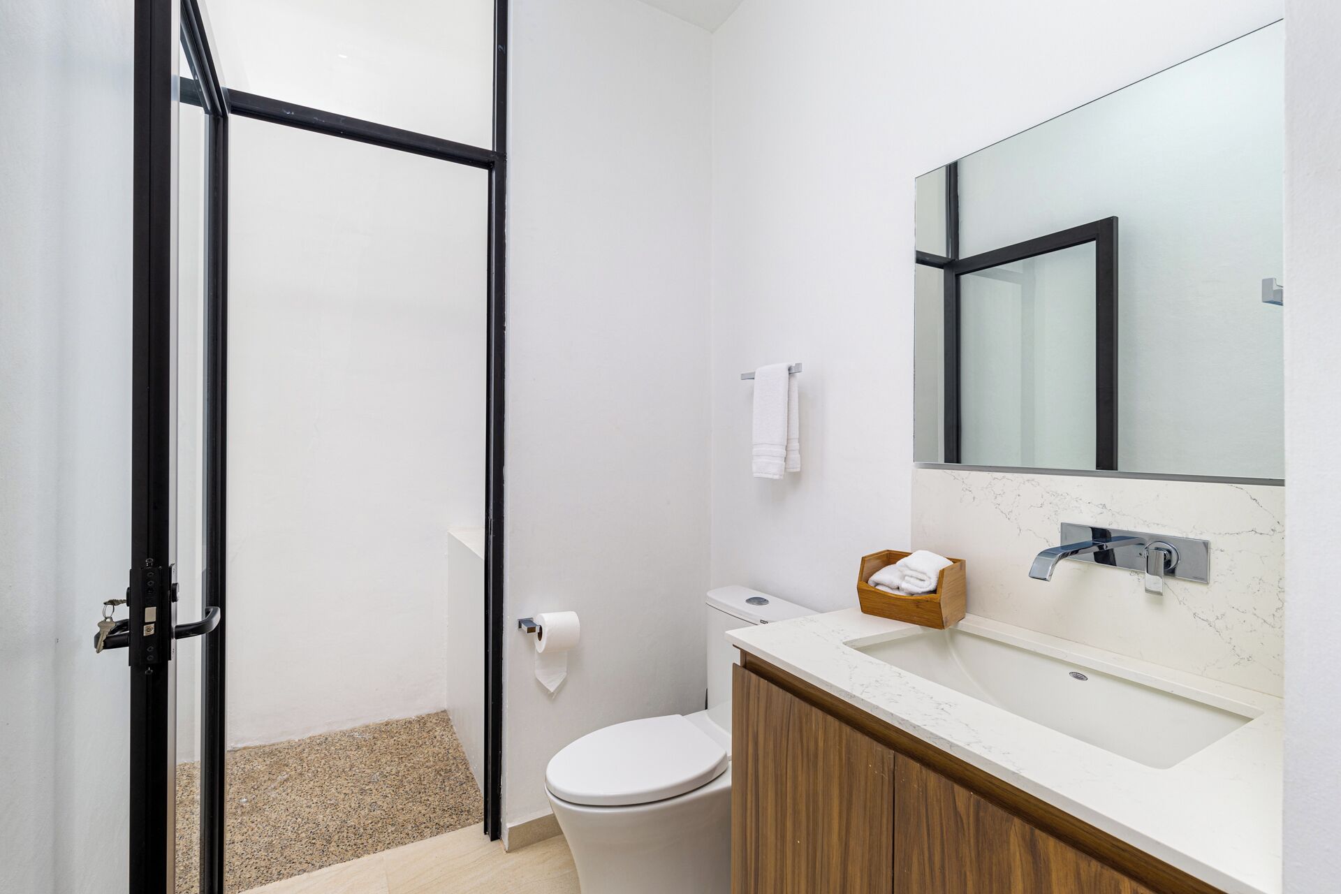 Een moderne badkamer met toilet, wastafel en spiegel.