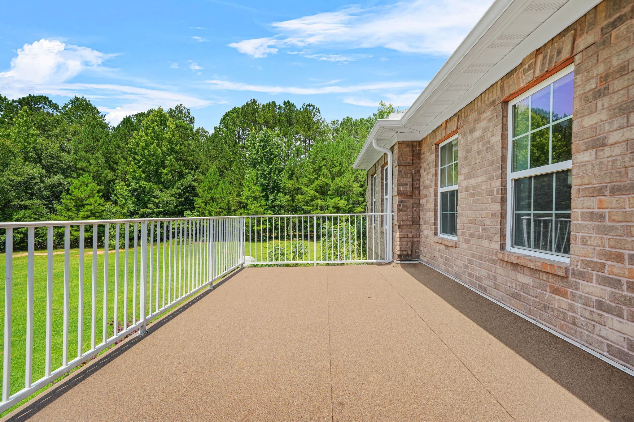 A balcony with a view of a grassy area and trees.