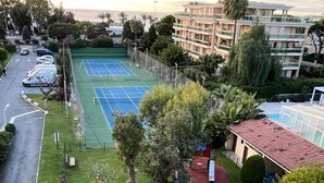 A residential area with a tennis court, a swimming pool, and a multi-story building.
