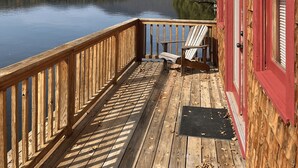A wooden deck with a view of a calm lake and distant hills. - The Point House - Exclusive Lake Placid Boat-Access Home (Lake Placid)