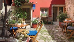 Une terrasse extérieure avec un sol en pierre, des meubles en bois et des plantes en pot.