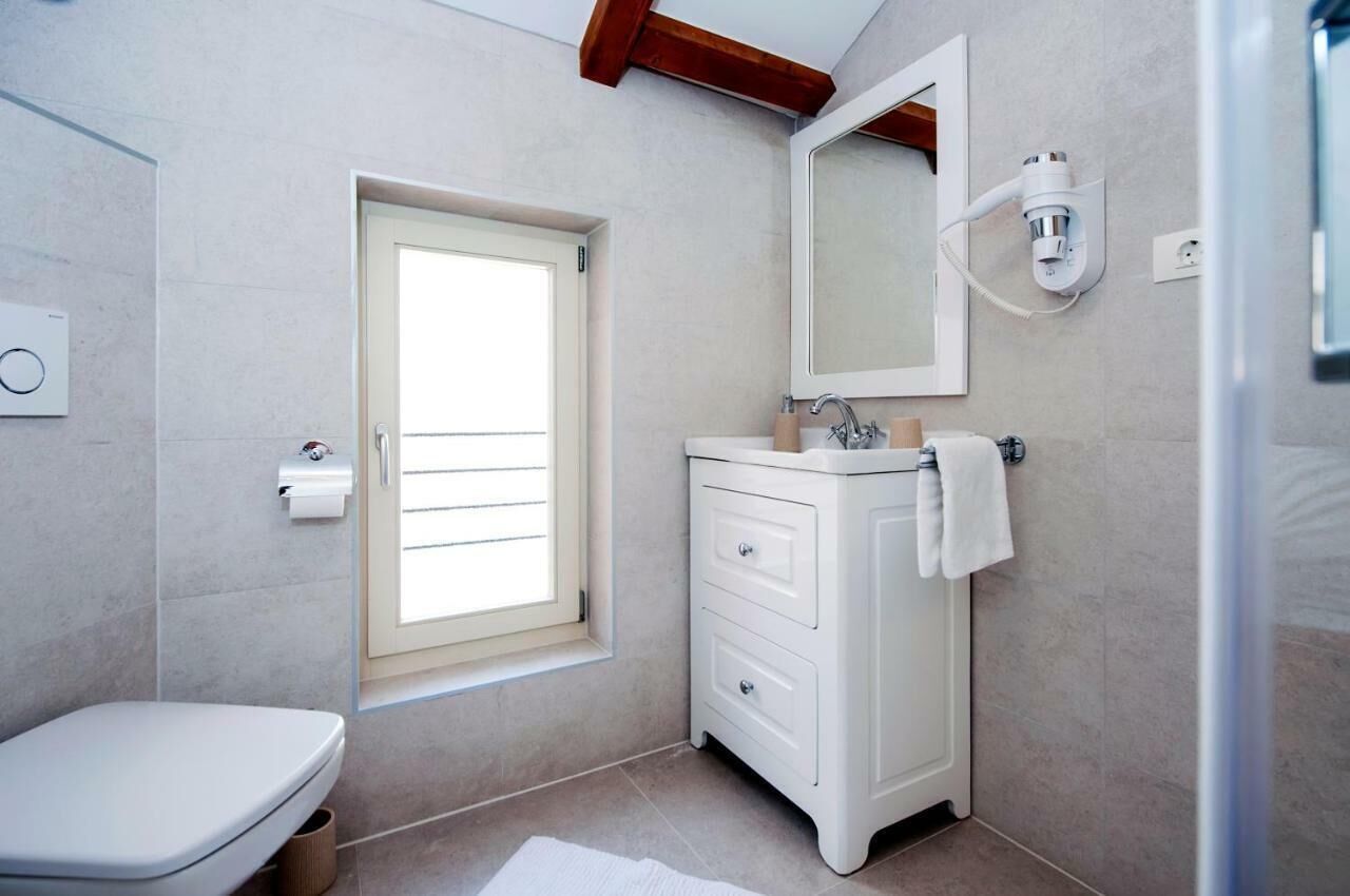 Une salle de bain avec des toilettes, un lavabo avec un miroir et une fenêtre.