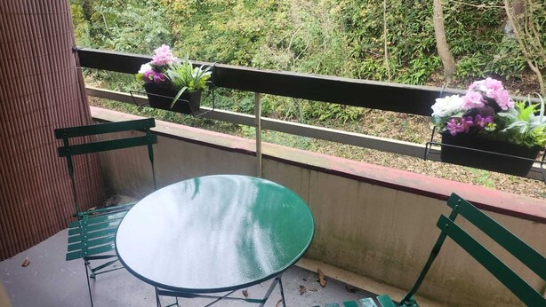 A balcony with a round table and two chairs, surrounded by a metal railing. - Getaway for two: cosy apartment with balcony (Trouville-sur-Mer)