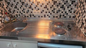 A kitchen with a stainless steel sink, two burners, and a tiled backsplash. - Getaway for two: cosy apartment with balcony (Trouville-sur-Mer)