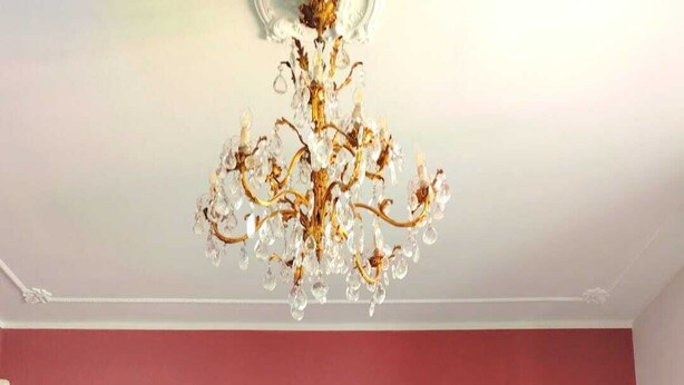 A bedroom with a large bed, white bedding, a chandelier, and two bedside tables with lamps.