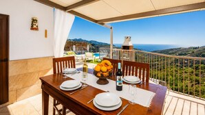 A dining table set for two with plates, cutlery, a wine bottle, and a fruit bowl.