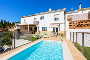Une maison à deux étages dotée d’une piscine, d’un espace salon extérieur et d’un patio couvert.