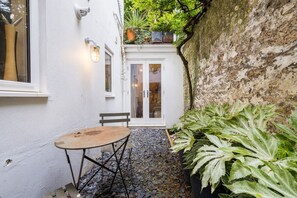Enjoy a charming courtyard with a round table for dining or socializing, surrounded by lush greenery and a warm ambiance.