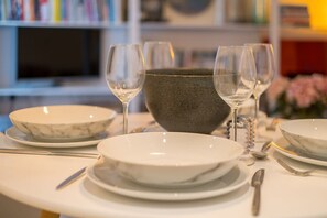 A dining table set with white plates, bowls, and wine glasses, with a large ceramic bowl in the center. - Host Stay Osbourne Rest (Hove)