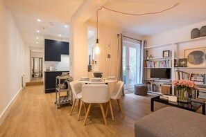 Cozy living space with a central dining area, bookshelf, and mounted TV.