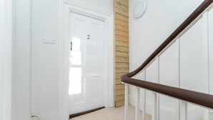 A hallway with a white door marked with the number 2, a wooden wall panel, and a white railing. - Host Stay Grafton Suite (Brighton)