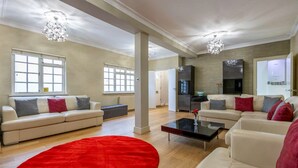 Een ruime woonkamer met twee witte banken, een rood vloerkleed en een zwarte salontafel.