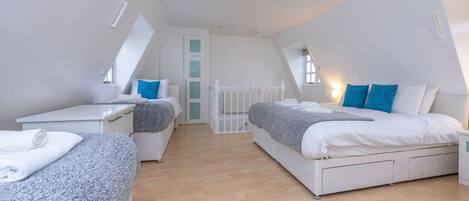 A modern, well-lit bedroom with two beds, a small desk, and a white radiator.
