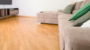 Un soggiorno con un divano beige, un armadietto in legno e un televisore piatto montato a parete.