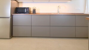 Una cucina moderna con un forno a microonde integrato, un lavello e un piano di lavoro in legno.