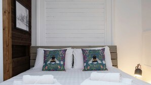 A neatly made bed with white linens and two decorative pillows with a bee design. - Host Stay Grafton Driftwood (Brighton)