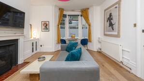 A living room with a grey sofa, a fireplace, a television, and a large window with curtains. - Host Stay Grafton Driftwood (Brighton)