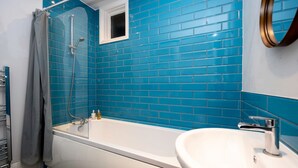 A bathroom with a white bathtub, a white sink, and a shower with a glass door. - Host Stay Grafton Driftwood (Brighton)