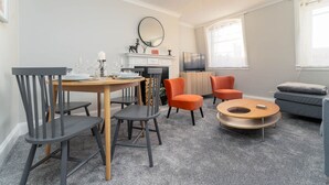 A modern living room with a dining table, chairs, a sofa, a coffee table, and a fireplace. - Host Stay Portland Apartment (Brighton)