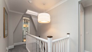 A staircase with a white railing, a ceiling light fixture, and a door leading to another room. - Host Stay Portland Apartment (Brighton)