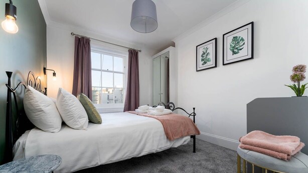 A bedroom with a bed, bedside table, and a window with curtains. - Host Stay Portland Apartment (Brighton)
